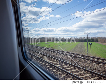 【ポーランド】郊外を走る鉄道の車窓から望む広大な田畑と雲が漂う空 103433922