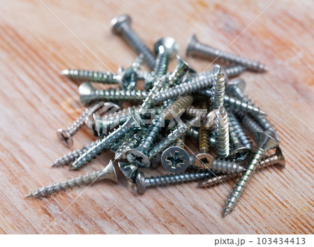 Bunch of different screws on a wooden surface 103434413
