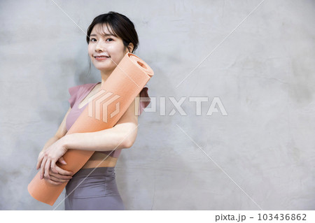 ヨガマットを持って立つ若い女性　ヨガイメージ 103436862