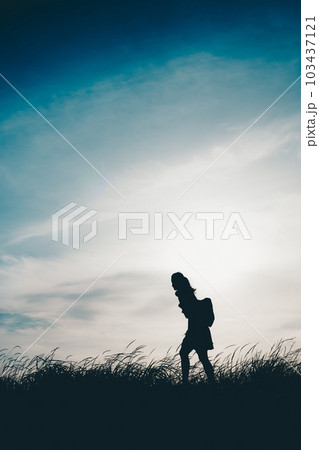 土手沿いを歩いているシルエットの女子高生 103437121