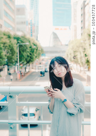 街中でスマホを持って佇む女性 103437728