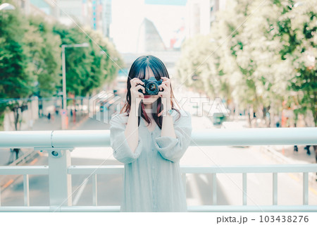 フィルムカメラを持って佇む女性 103438276