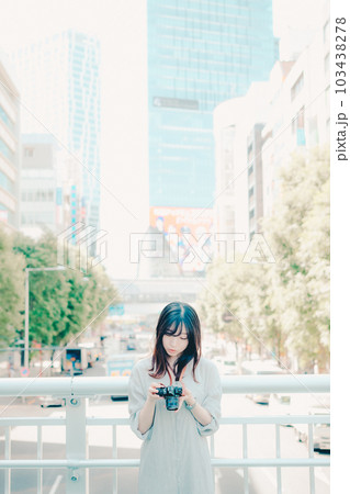 フィルムカメラを持って佇む女性 103438278