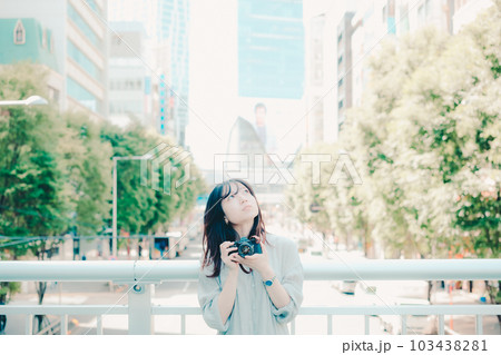 フィルムカメラを持って佇む女性 103438281