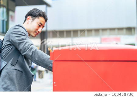 ポストに郵便物を投函する男性 103438730