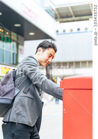 ポストに郵便物を投函する男性 103438732