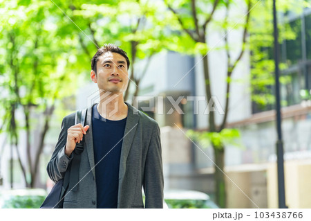 新緑の市街地を歩く男性 103438766