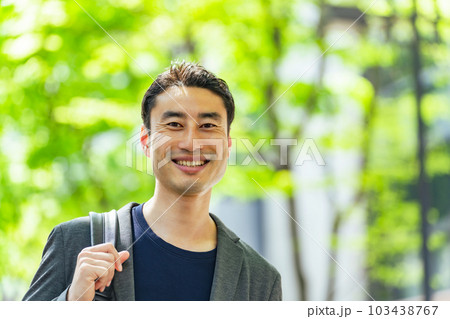 新緑の市街地を歩く男性 103438767