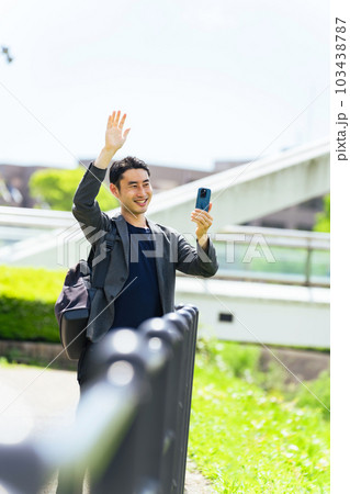 手を振ってスマホで撮影する男性 103438787