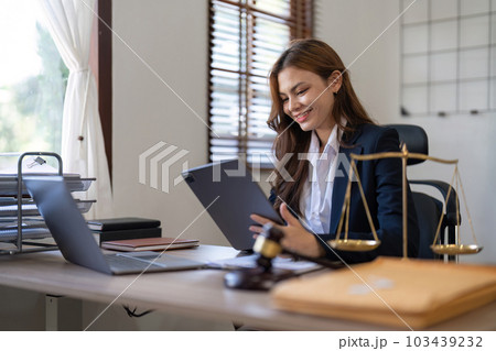 Attractive young lawyer in office Business woman and lawyers discussing contract papers with brass scale on wooden desk in office. Law, legal services, advice, Justice and real estate concept Attractive young lawyer in office Business woman and lawyers discussing contract papers with brass scale on wooden desk in office. Law, legal services, advice, Justice and real estate concept 103439232