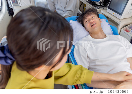 救急車で運ばれる若い男性 付添う妻 救急車で運ばれる若い男性 付添う妻 103439665
