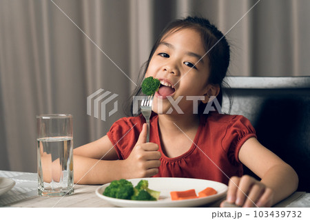 Asian little girl eating healthy vegetables with relish. 103439732