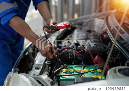 Close up technician uses multimeter voltmeter to check voltage level in car battery. Service and Maintenance car battery. Close up technician uses multimeter voltmeter to check voltage level in car battery. Service and Maintenance car battery. 103439855