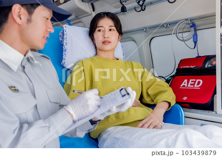 救急車を呼んだ体調不良の女性に質問をする救急隊員 救急車を呼んだ体調不良の女性に質問をする救急隊員 103439879