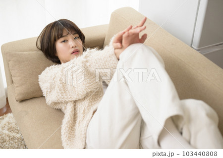 ソファに寝そべる若い女性 103440808