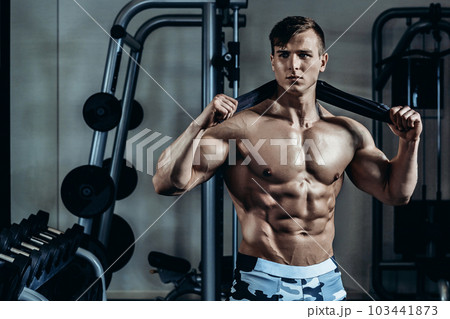Young muscular man with a towel around his neck after training at the gym Young muscular man with a towel around his neck after training at the gym 103441873