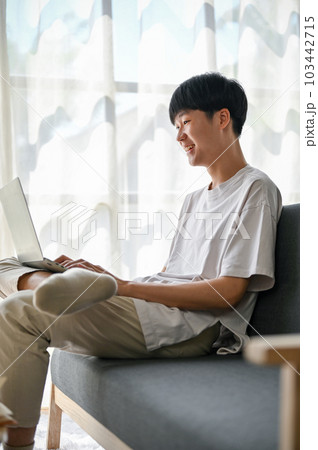 Side view, A happy young Asian man is watching videos on social media on his laptop 103442715