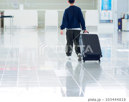 空港でスーツケースを持って旅行に出発する男性の後ろ姿 空港でスーツケースを持って旅行に出発する男性の後ろ姿 103444818