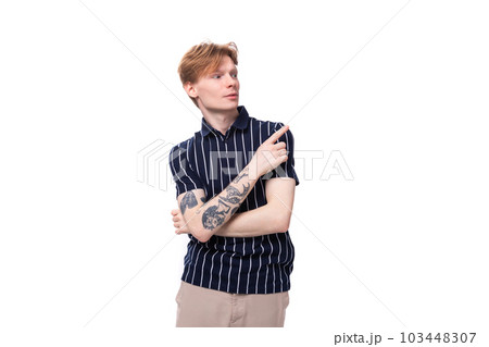 handsome 25 year old blond male with tattoos in a striped polo points his finger to the side handsome 25 year old blond male with tattoos in a striped polo points his finger to the side 103448307