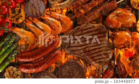 Top shot of various types of meat on garden grill with roaring flames 103448977