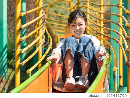 公園のすべり台で遊ぶ小学生の女子 103451790