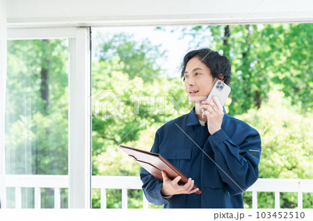 スマホで連絡する作業着を着たスタッフ スマホで連絡する作業着を着たスタッフ 103452510