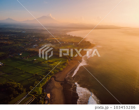 Aerial view of coastline with volcano, warm sunrise or sunset tones and ocean in Bali 103453286