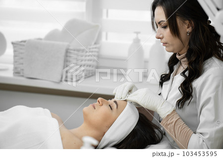 Professional care: cosmetology at a high level, when a qualified specialist cleanses the skin and provides comprehensive care for the appearance of a woman in a beauty clinic 103453595
