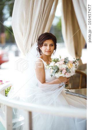 Beautiful bride with wedding flowers bouquet, attractive woman in wedding dress. Happy newlywed woman. 103457477