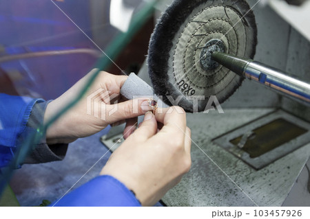 Jewelry industry. Hands make a golden decoration. Grinds the ring. 103457926