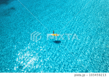 Aerial view of with man and woman on sup board in blue sea Aerial view of with man and woman on sup board in blue sea 103459213