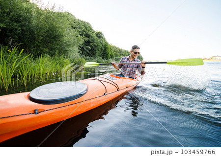 A young Caucasian man sits in a kayak and paddles. The concept of water entertainment. 103459766