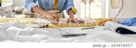 African-American seamstress draws pattern on fabric with tailors chalk at large cutting table African-American seamstress draws pattern on fabric with tailors chalk at large cutting table 103459857