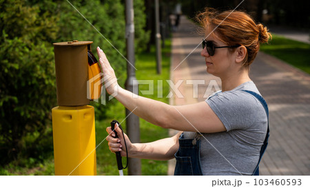 Blind woman pressing a button for a traffic light. Blind woman pressing a button for a traffic light. 103460593