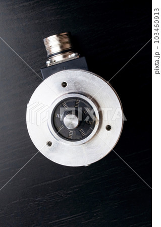 Metal encoder on a black wooden table Metal encoder on a black wooden table 103460913
