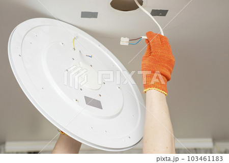 An electrician installs a chandelier on the ceiling. An electrician installs a chandelier on the ceiling. 103461183