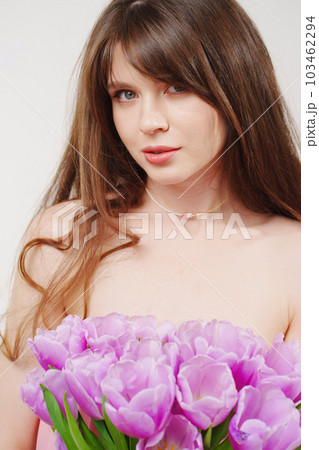 portrait of a woman topless with a bouquet of tulips on a white background. 103462294