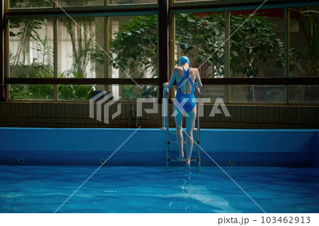 Back view on woman in swimsuit getting out from pool using ladder Back view on woman in swimsuit getting out from pool using ladder 103462913