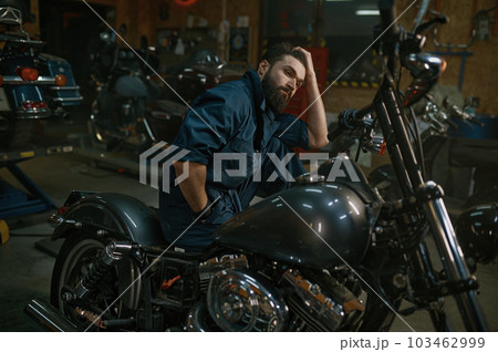 Portrait of brutal mechanic sitting on repaired motorcycle Portrait of brutal mechanic sitting on repaired motorcycle 103462999