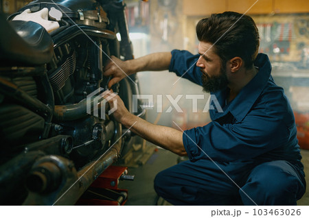 Young mechanic working on motorcycle in garage repair service Young mechanic working on motorcycle in garage repair service 103463026