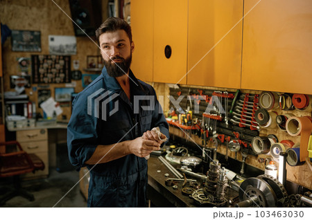 Portrait of serviceman looking aside standing over garage workshop interior 103463030