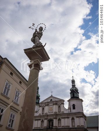 【ポーランド】クラクフ旧市街にある教会前に立つ石柱の上の石像と曇り空 103464601