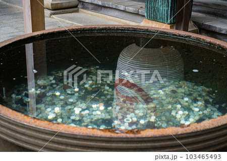 賽銭の入った水瓶の水面に反射する提灯 103465493
