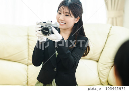 出張買取訪問でカメラを査定する若い女性 出張買取訪問でカメラを査定する若い女性 103465973