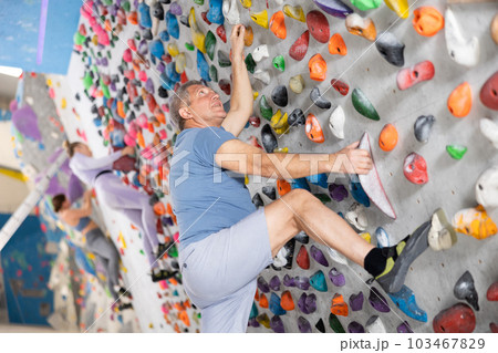 Adult man practicing rock climbing on climbing wall Adult man practicing rock climbing on climbing wall 103467829