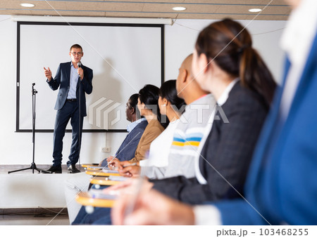 Business coach speaking from stage to audience at corporate training Business coach speaking from stage to audience at corporate training 103468255