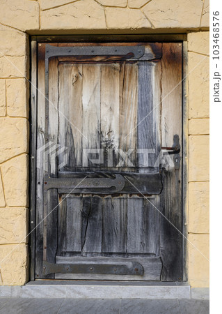 An old door made of blackened wood with vintage metal hinges 103468576