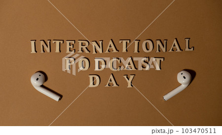 Announcement text INTERNATIONAL PODCAST DAY on beige background with wireless headphones. Podcasting concept. Listening radio audio healing wellness sound Announcement text INTERNATIONAL PODCAST DAY on beige background with wireless headphones. Podcasting concept. Listening radio audio healing wellness sound 103470511