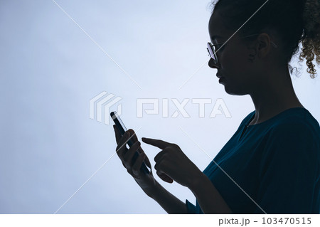 スマホを使う外国人女性のシルエット スマホを使う外国人女性のシルエット 103470515