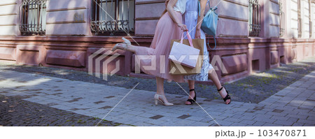 two girls in dresses and high hill shoes holding shopping bags 103470871